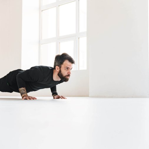 Confident mid aged white sportsman exercising in a bright room doing plank